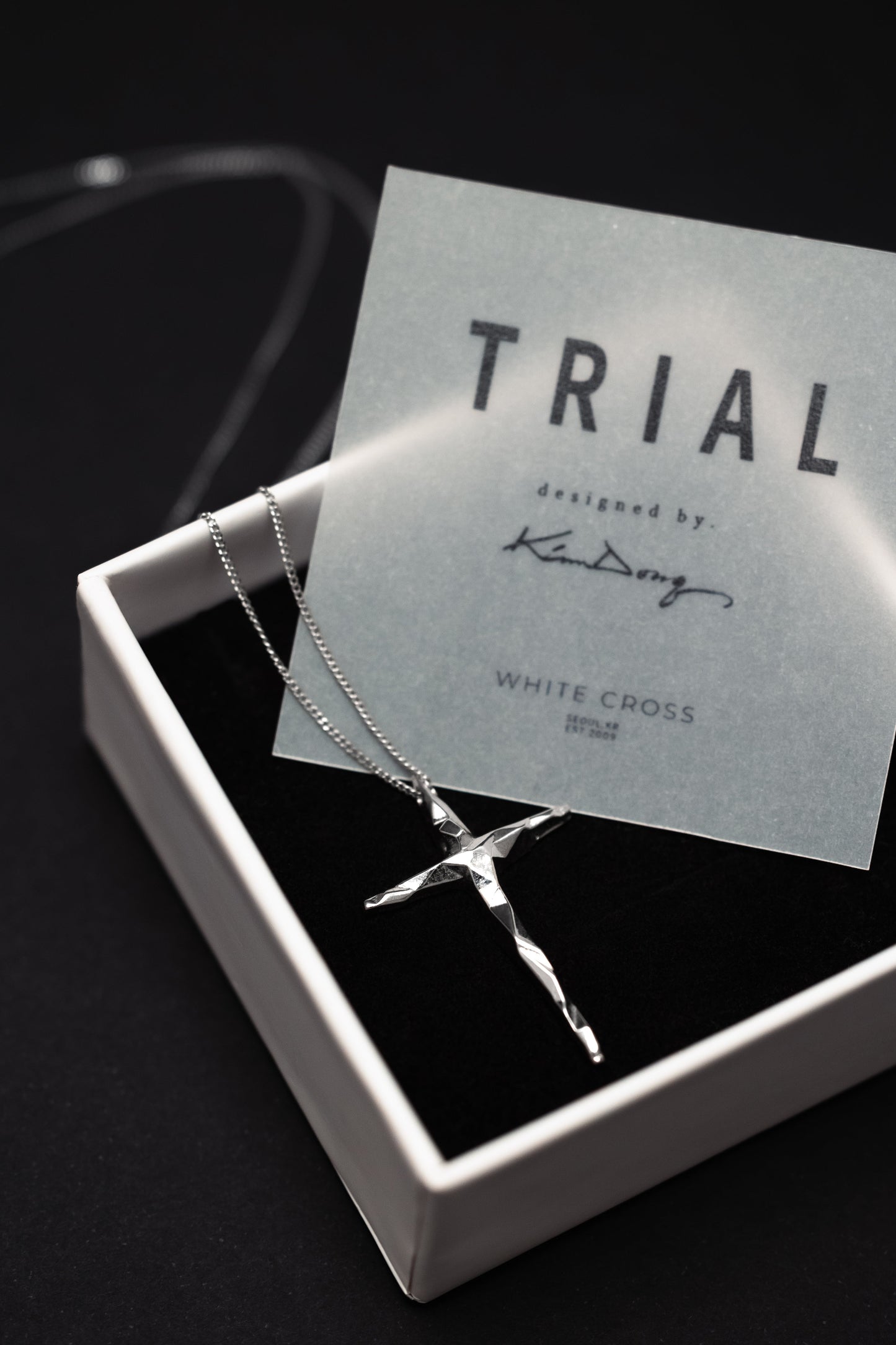 Silver cross necklace on a 'Trial' card in a box.